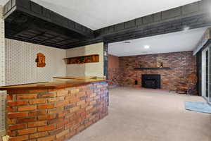 Bar with a dry bar, a wood stove, carpet, and brick wall