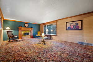 Carpeted living area featuring visible vents, a textured ceiling, and crown molding