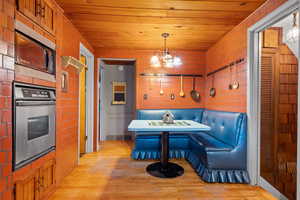 Kitchen featuring stainless steel oven, wood ceiling, light wood-style floors, and black microwave