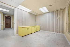 Spare room with light colored carpet, visible vents, and a drop ceiling