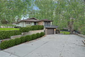 View of front of house featuring a garage, a balcony, concrete driveway, and fence