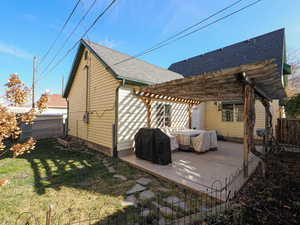 Exterior space featuring a shingled roof, fence, a lawn, a patio area, and a pergola