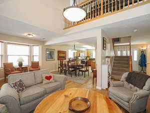 Living room featuring stairway, baseboards, light wood-type flooring, and a textured ceiling