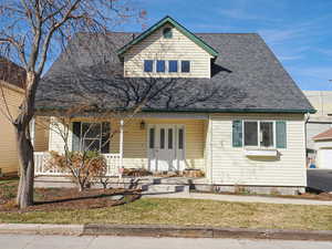 View of front of property featuring a garage, a porch, french doors, and a shingled roof