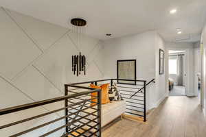 Hallway with recessed lighting, baseboards, an upstairs landing, and light wood-style floors
