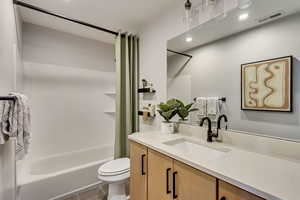 Full bath with visible vents, toilet, tile patterned flooring, shower / bath combination with curtain, and vanity