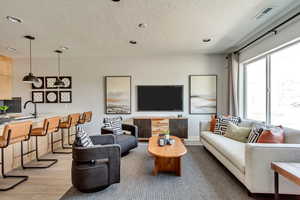 Living room featuring recessed lighting, visible vents, a textured ceiling, and light wood-style flooring