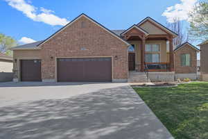 Ranch-style house featuring a porch, concrete driveway, brick siding, an attached garage, and a front yard