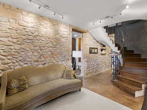 Living area featuring stairway, rail lighting, and finished concrete floors