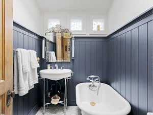 Main-level bathroom featuring a sink, a wainscoted wall, and a freestanding bath