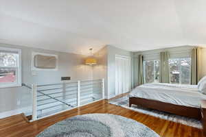 Bedroom with lofted ceiling, wood finished floors, baseboards, and a closet