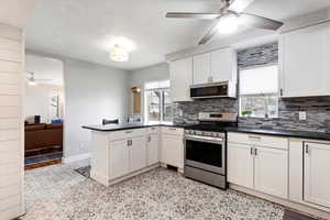 Kitchen with dark countertops, backsplash, ceiling fan, a peninsula, and stainless steel appliances