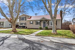 Tri-level home featuring a chimney, a front yard, and fence