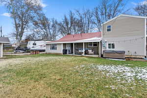 Back of house with a patio area, fence, a lawn, and a hot tub