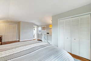 Bedroom with a closet, baseboards, wood finished floors, and vaulted ceiling