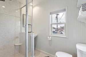 Bathroom with toilet, baseboards, and a stall shower