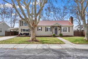 View of front of house with a carport, concrete driveway, fence, and a front lawn