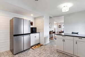 Kitchen with wooden walls, dark countertops, and freestanding refrigerator