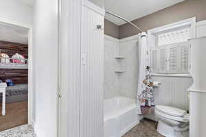 Full bathroom with tile patterned floors, toilet, and shower / bath combo with shower curtain