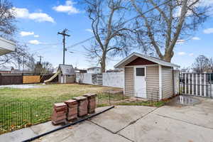 View of patio / terrace with an outbuilding, a storage unit, and a fenced backyard