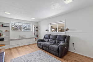 Living room with a wainscoted wall, a textured ceiling, and wood finished floors