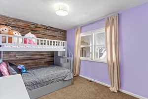 Carpeted bedroom featuring wooden walls, visible vents, and baseboards