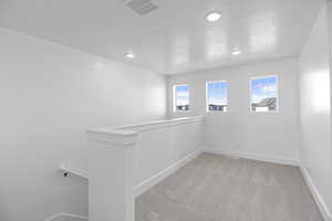 Spare room with visible vents, light carpet, a textured ceiling, recessed lighting, and baseboards