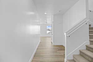 Hall featuring stairway, baseboards, recessed lighting, a textured ceiling, and light wood-type flooring