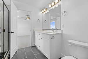 Full bathroom with a shower stall, toilet, a ceiling fan, and a sink