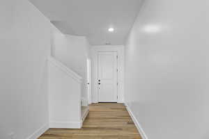 Hallway with stairs, baseboards, light wood finished floors, and a textured ceiling