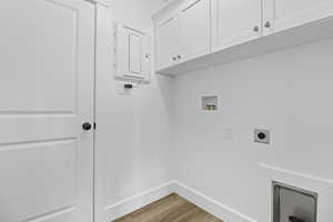 Laundry room with electric panel, hookup for a washing machine, wood finished floors, cabinet space, and hookup for an electric dryer