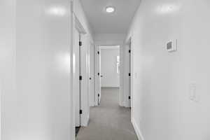 Hallway with baseboards and carpet