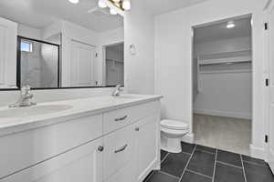 Full bathroom with a sink, a spacious closet, a stall shower, and tile patterned floors