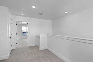 Interior space with visible vents, an upstairs landing, a textured ceiling, carpet flooring, and baseboards