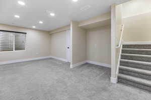 Finished basement with visible vents, recessed lighting, stairway, carpet flooring, and baseboards