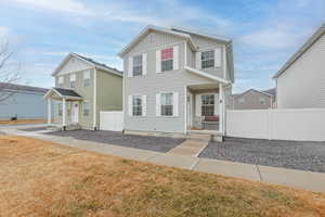 Traditional-style home with board and batten siding, a front yard, and fence