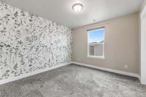 Spare room featuring visible vents, baseboards, a textured ceiling, and carpet flooring