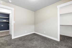 Unfurnished bedroom featuring visible vents, baseboards, and dark colored carpet