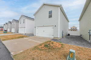 View of front of house featuring fence, central AC, concrete driveway, a garage, and a residential view