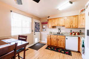 Kitchen with a sink, light brown cabinetry, white dishwasher, and light wood finished floors