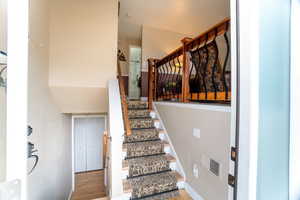 Stairway featuring visible vents, baseboards, and wood finished floors