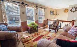 Living area featuring an inviting chandelier, baseboards, and carpet