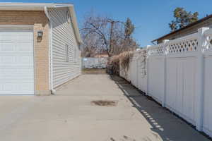 View of property exterior featuring brick siding, a garage, and fence