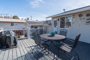 Wooden deck featuring outdoor dining space and a grill