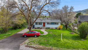 View of front of house featuring fence, a mountain view, driveway, and a front yard
