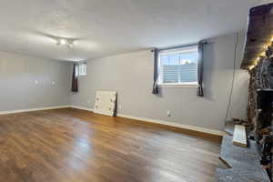 Below grade area featuring a textured ceiling, baseboards, and wood finished floors