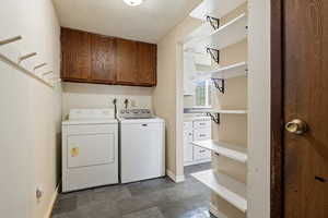 Laundry room featuring a textured ceiling, baseboards, washing machine and dryer, and cabinet space