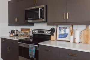 Kitchen featuring light countertops, tasteful backsplash, and appliances with stainless steel finishes