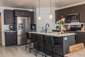 Kitchen with a sink, stainless steel appliances, a kitchen bar, and light countertops