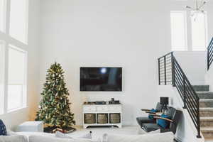 Living area with stairway, an inviting chandelier, and a towering ceiling